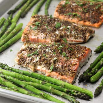 Close up of baked salmon and asparagus on a metal sheet pan.