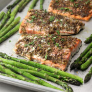 Close up of baked salmon and asparagus on a metal sheet pan.
