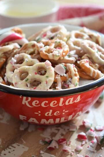 A red bowl of candy coated pretzels.