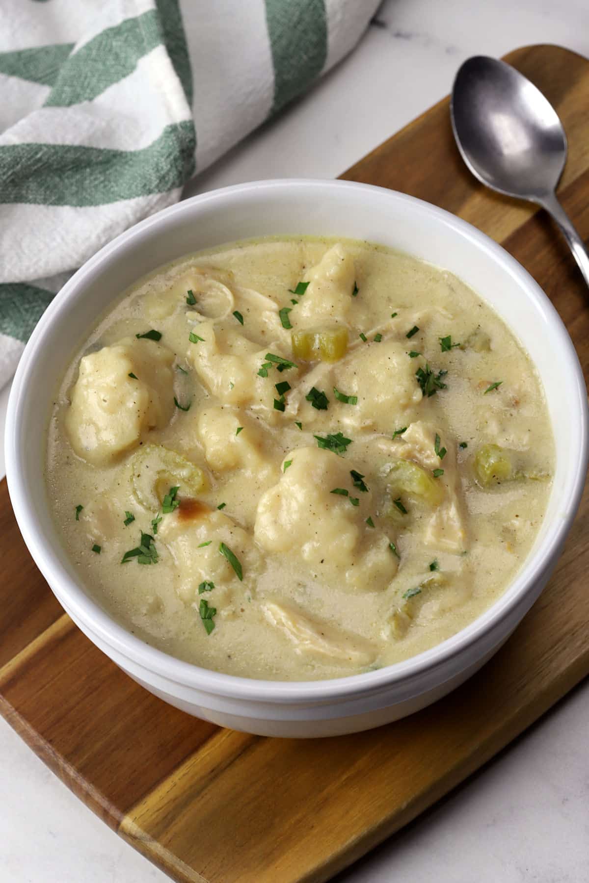 A white soup bowl filled with chicken and dumplings.