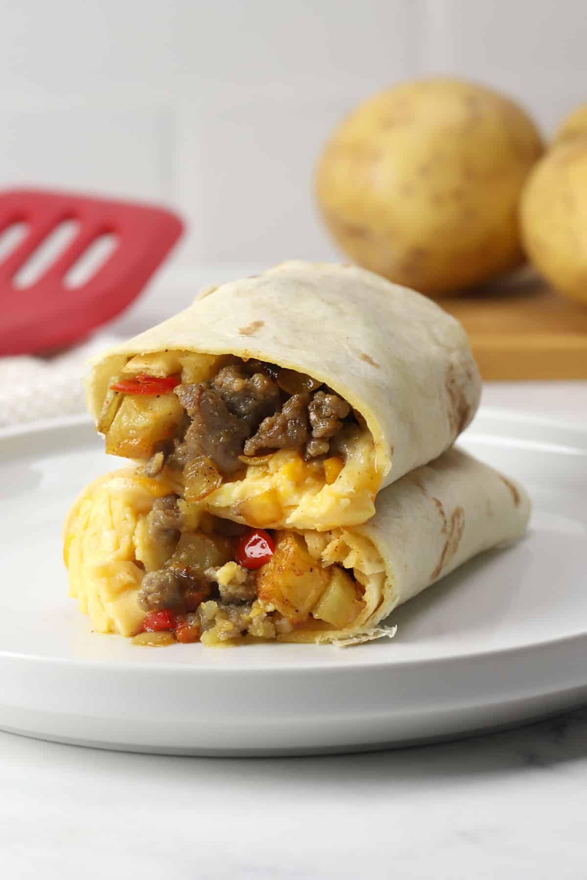 Two breakfast burrito halves stacked on a white plate.