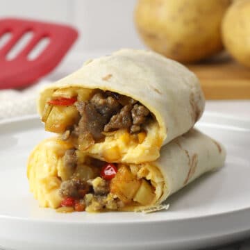 Two breakfast burrito halves stacked on a white plate.