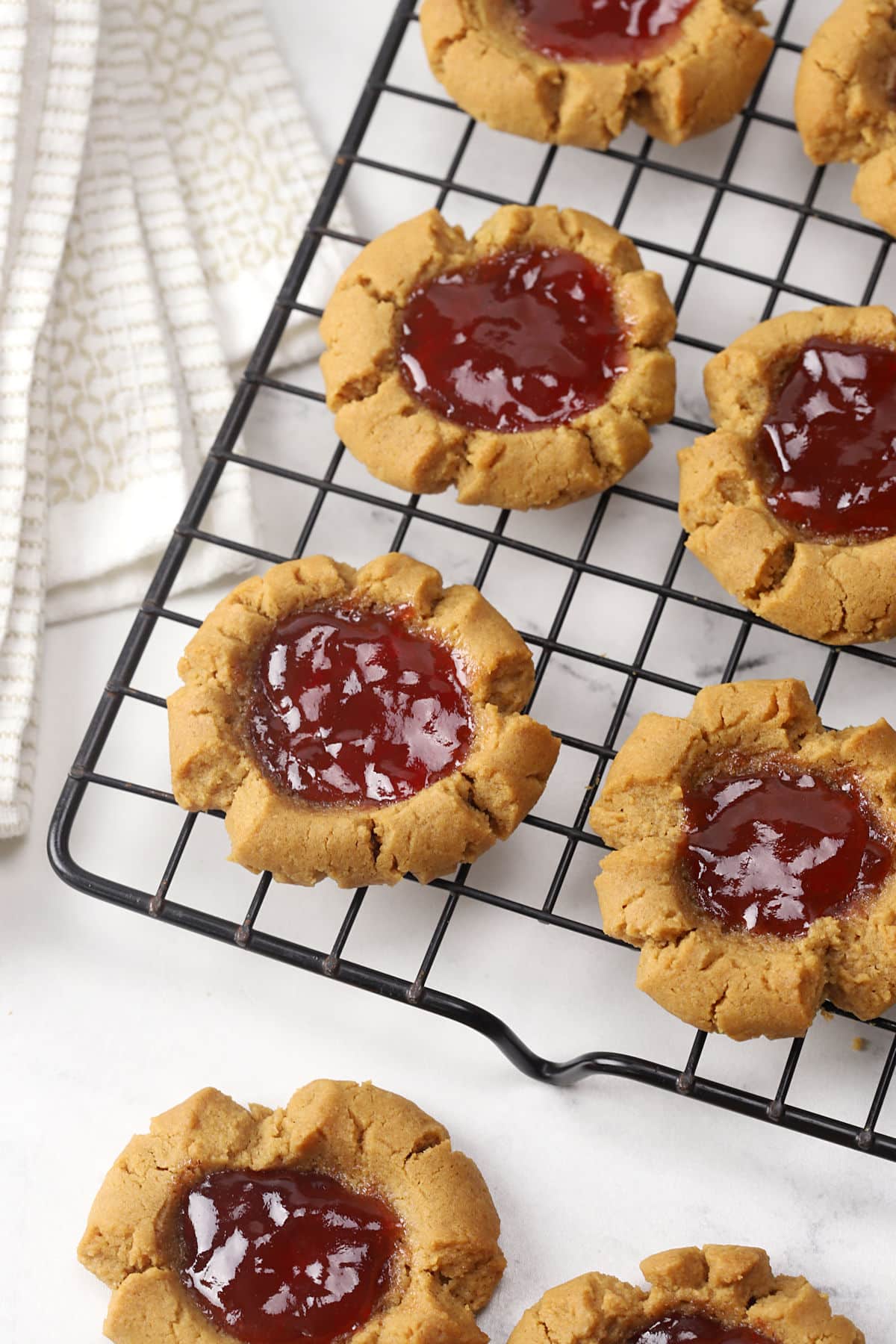 Peanut butter thumbprint cookies on a cooling rack.