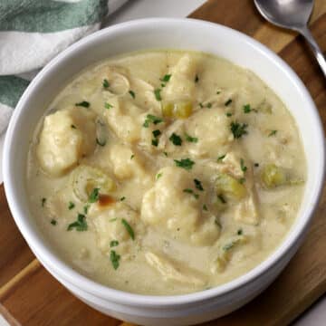 A white soup bowl filled with chicken and dumplings.