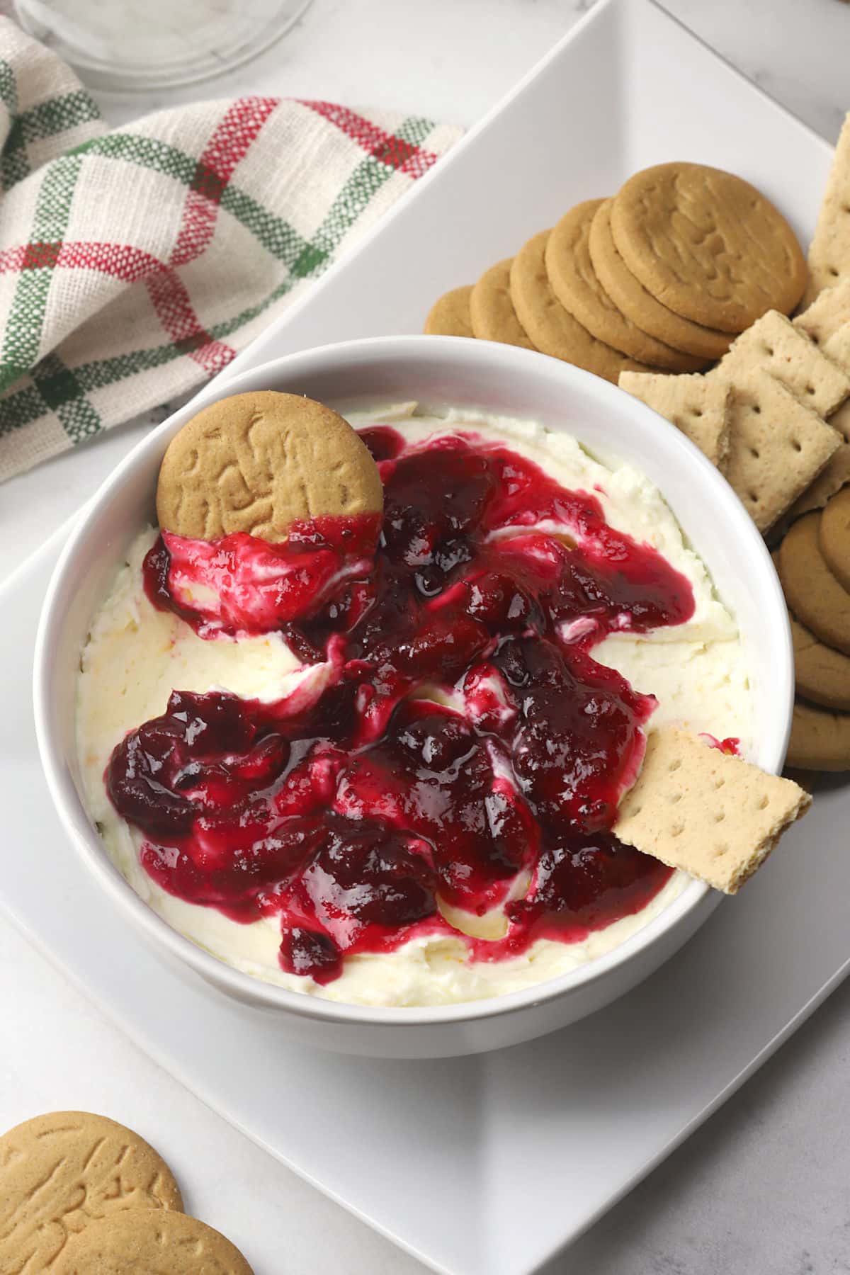 A bowl of cranberry cheesecake dip with ginger snap cookies and graham crackers.