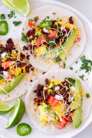 Three Mexican breakfast tacos on a white dish.
