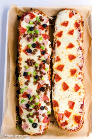 A baking sheet with two slices of french bread pizza.