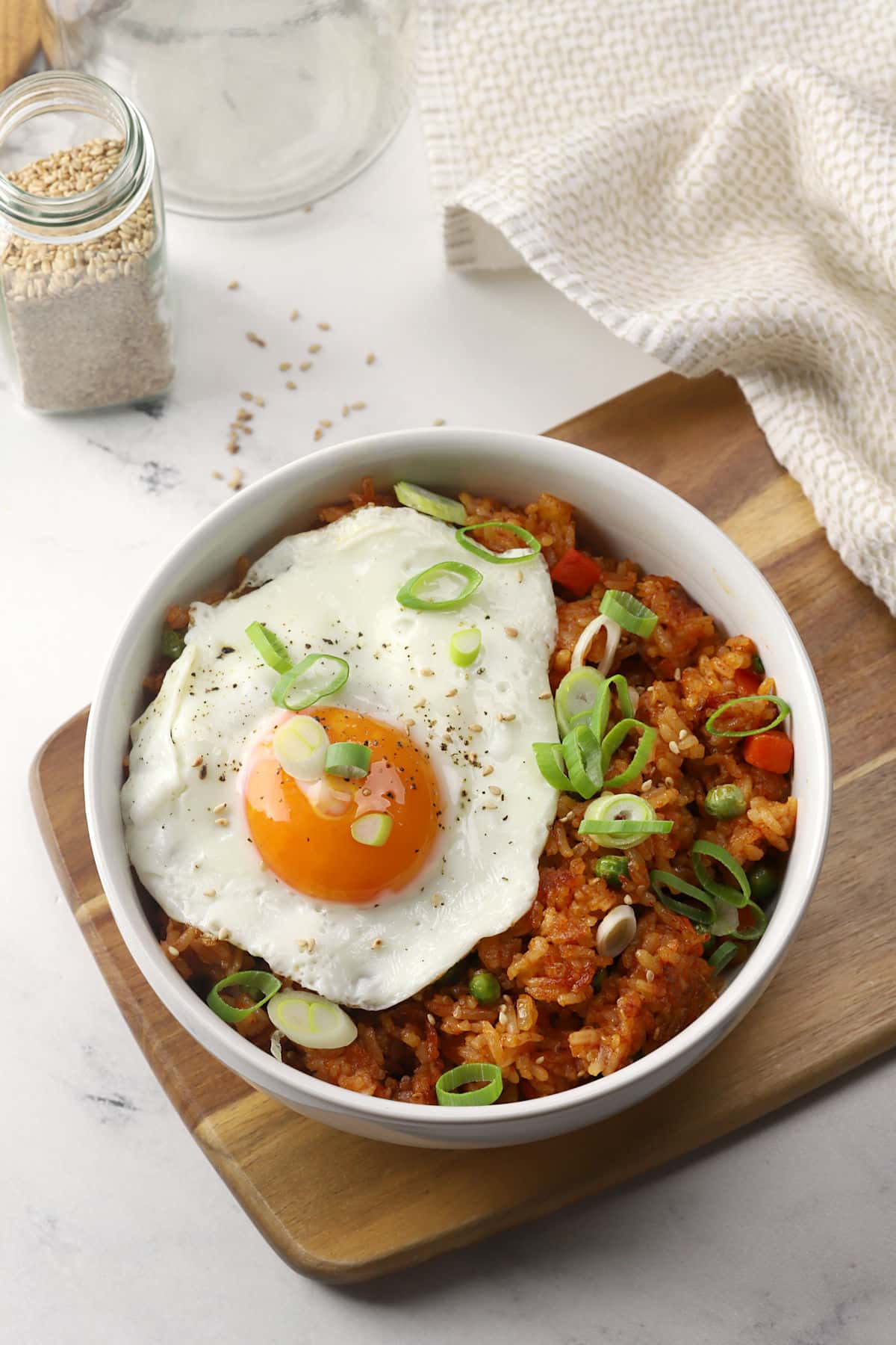 A white bowl filled with gochujang fried rice that's topped with a sunny-side-up egg.