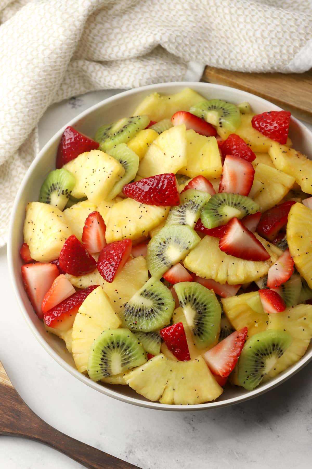 A bowl filled with spring fruit salad topped with poppy seed dressing.