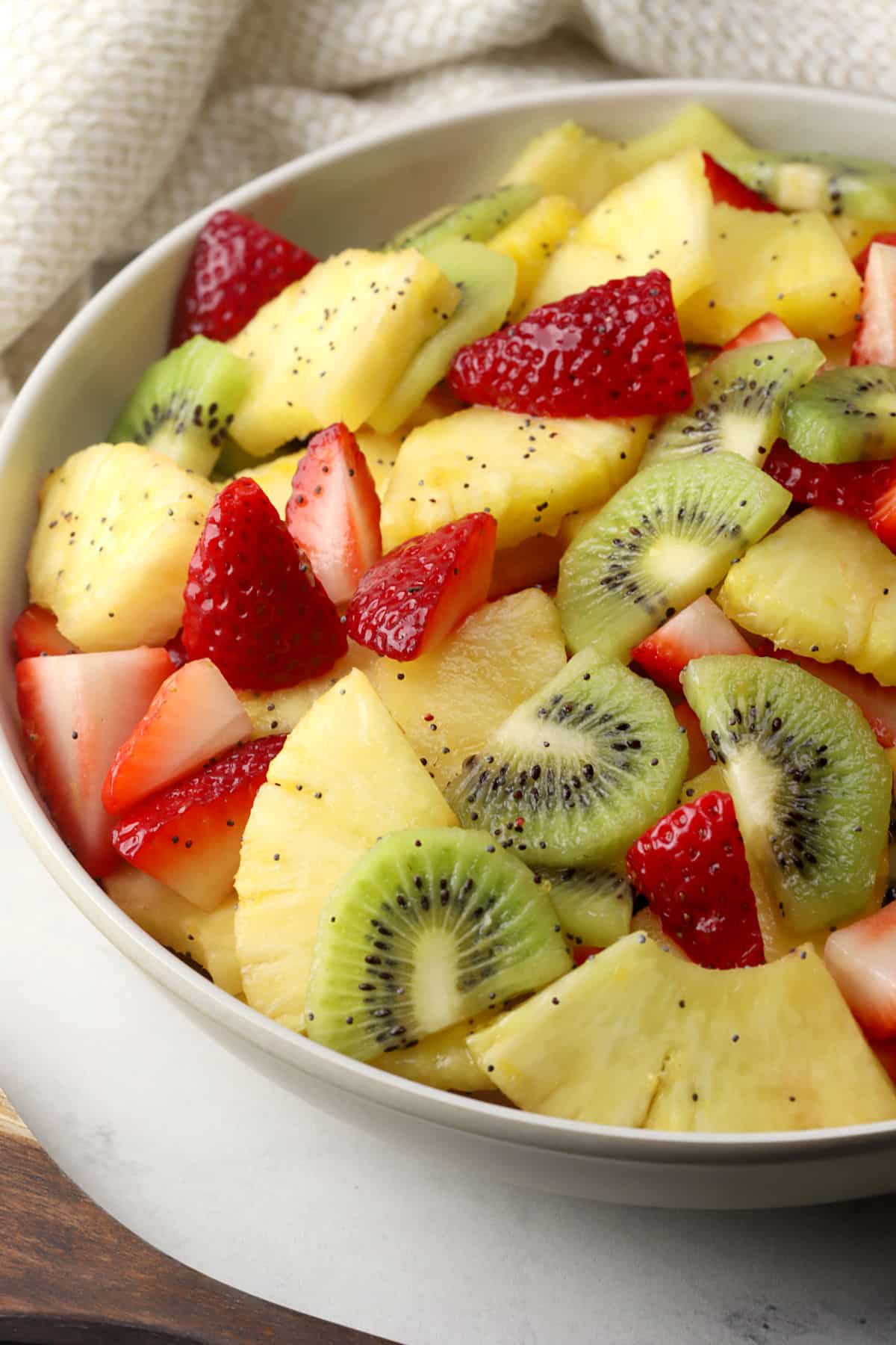 Close up of spring fruit salad made with strawberries, kiwi, and pineapple in a bowl.