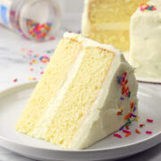 A slice of vanilla layer cake on a serving plate.