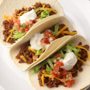 Three ground beef tacos on a serving plate.