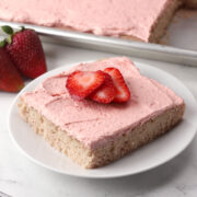 A slice of 13x18 strawberry sheet cake on a serving plate.