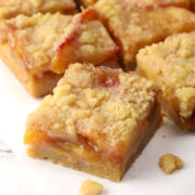 Close up of a sliced peach crumb bar on a countertop.