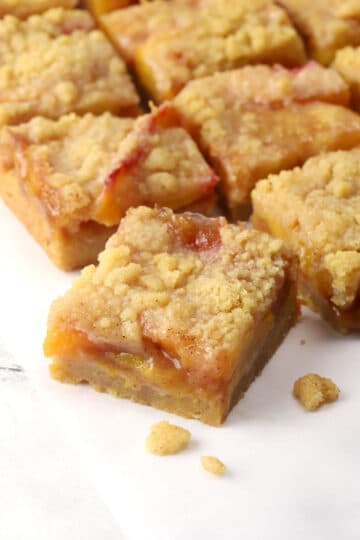 Close up of a sliced peach crumb bar on a countertop.