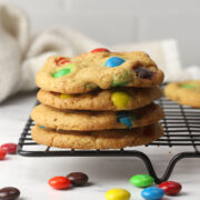 A stack of brown butter M&M cookies on a cooling rack.