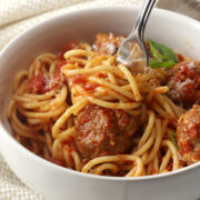 A bowl of homemade spaghetti and meatballs with a fork.