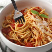 A bowl of spaghetti marinara with a fork.