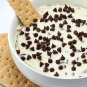 Serving bowl filled with chocolate chip cheesecake dip and a graham cracker.
