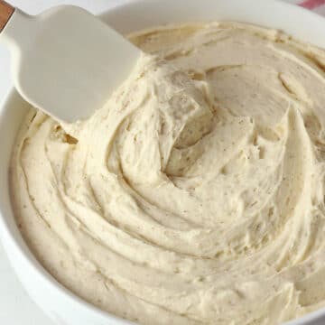 A spatula in a bowl of cinnamon buttercream frosting.