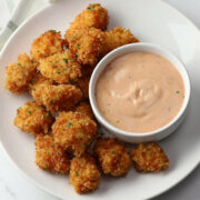 Homemade chicken nuggets on a plate with dipping sauce.