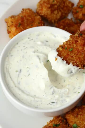 A chicken nugget being dipped into homemade ranch dip.