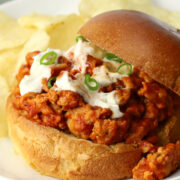A buffalo chicken sloppy joe on a plate with potato chips.