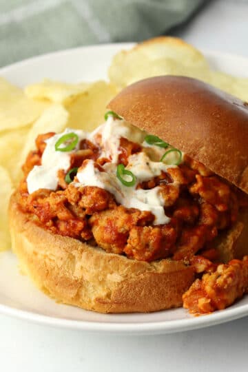 A buffalo chicken sloppy joe on a plate with potato chips.