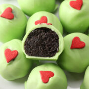 Split open grinch oreo ball on a stack of others.