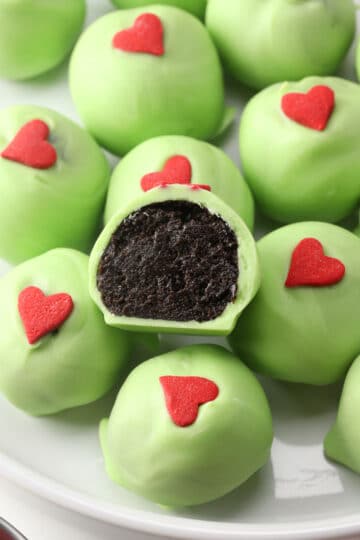 Split open grinch oreo ball on a stack of others.