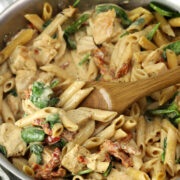 Scooping marry me chicken pasta from a pan.
