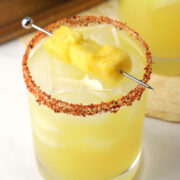 Close up of pineapple margarita with tajin rim and pineapple garnish.