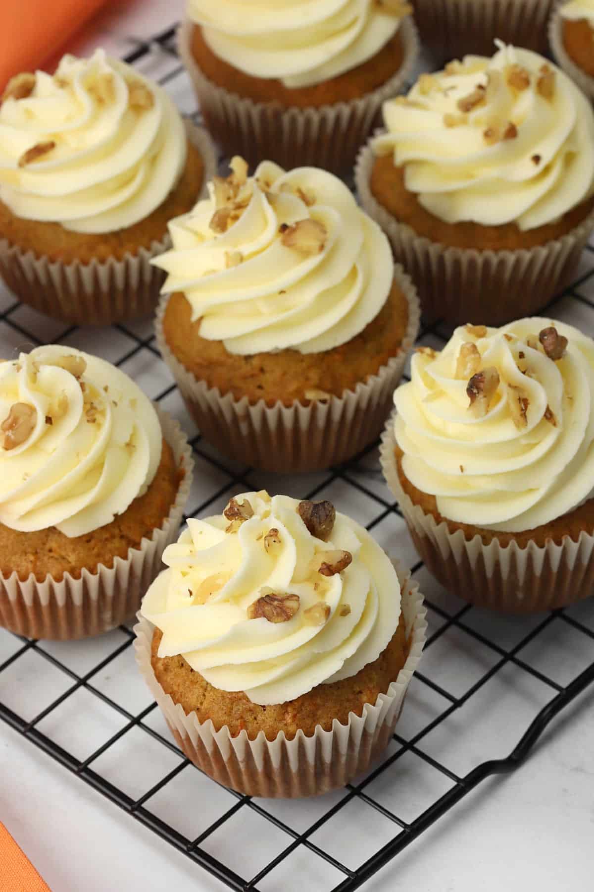 A batch of carrot cake cupcakes on a cooling rack.