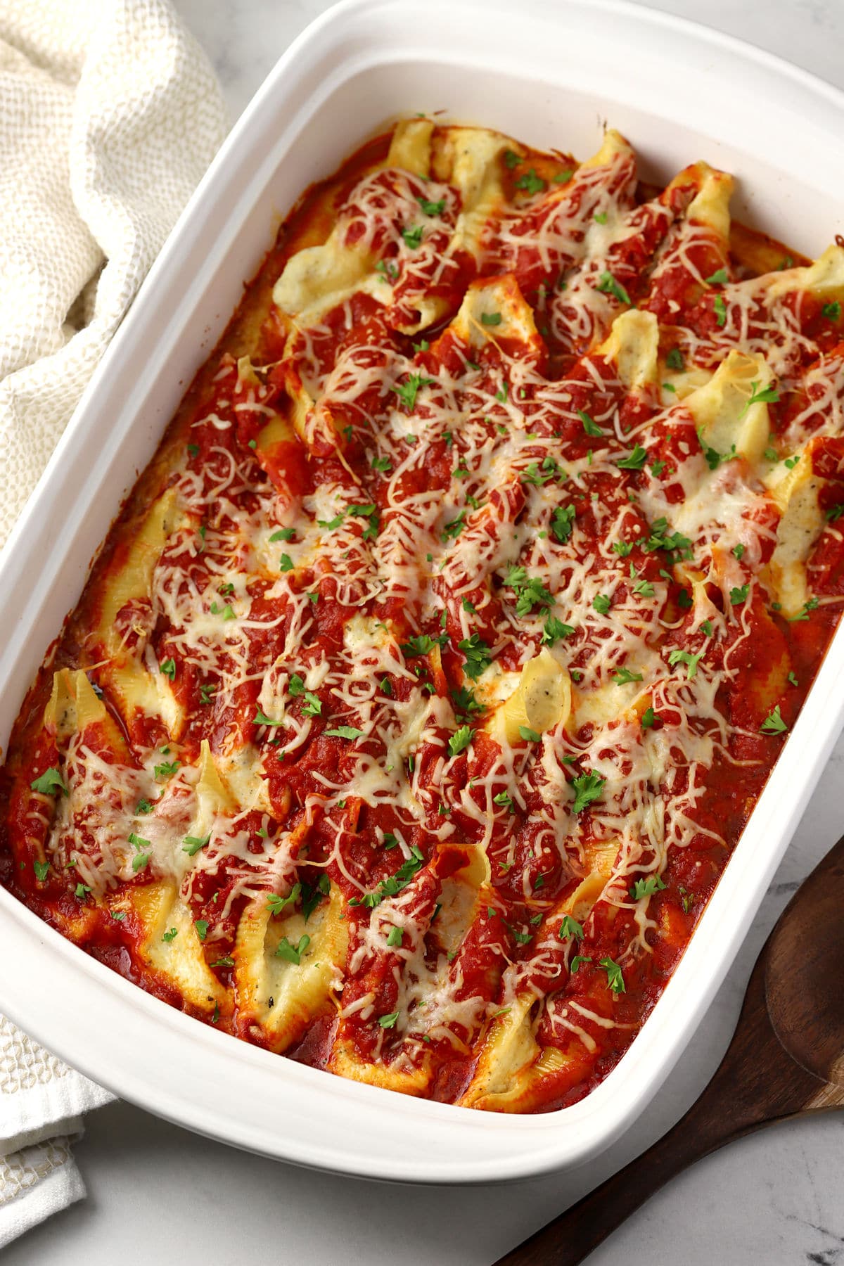 A white casserole dish filled with baked cheese stuffed shells.