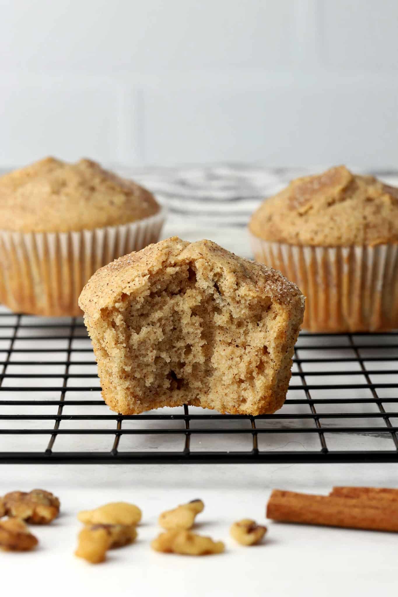 A muffin on a cooling rack with a bite taken out.