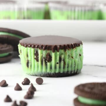A mint chocolate chip mini cheesecake unwrapped on a cutting board.