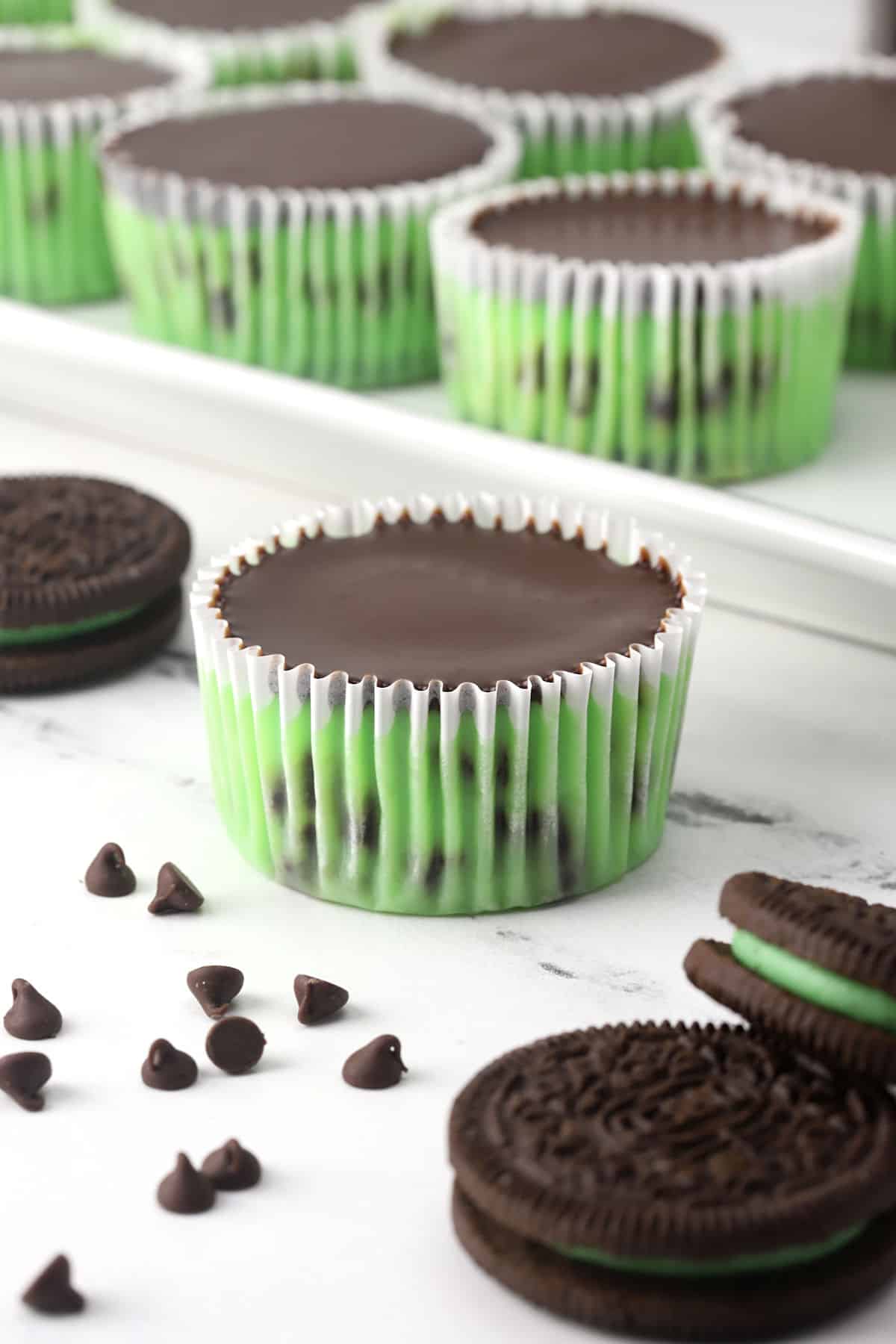 A mint chocolate chip mini cheesecake with mint Oreos in the foreground.
