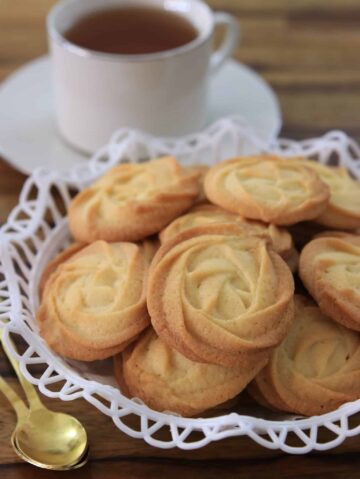 A stack of butter cookies on a decorative serving platter.