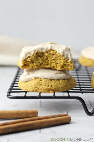 Soft, iced cookies stacked on a cooling rack.