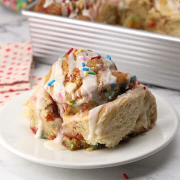 A birthday cookie cinnamon roll on a plate.