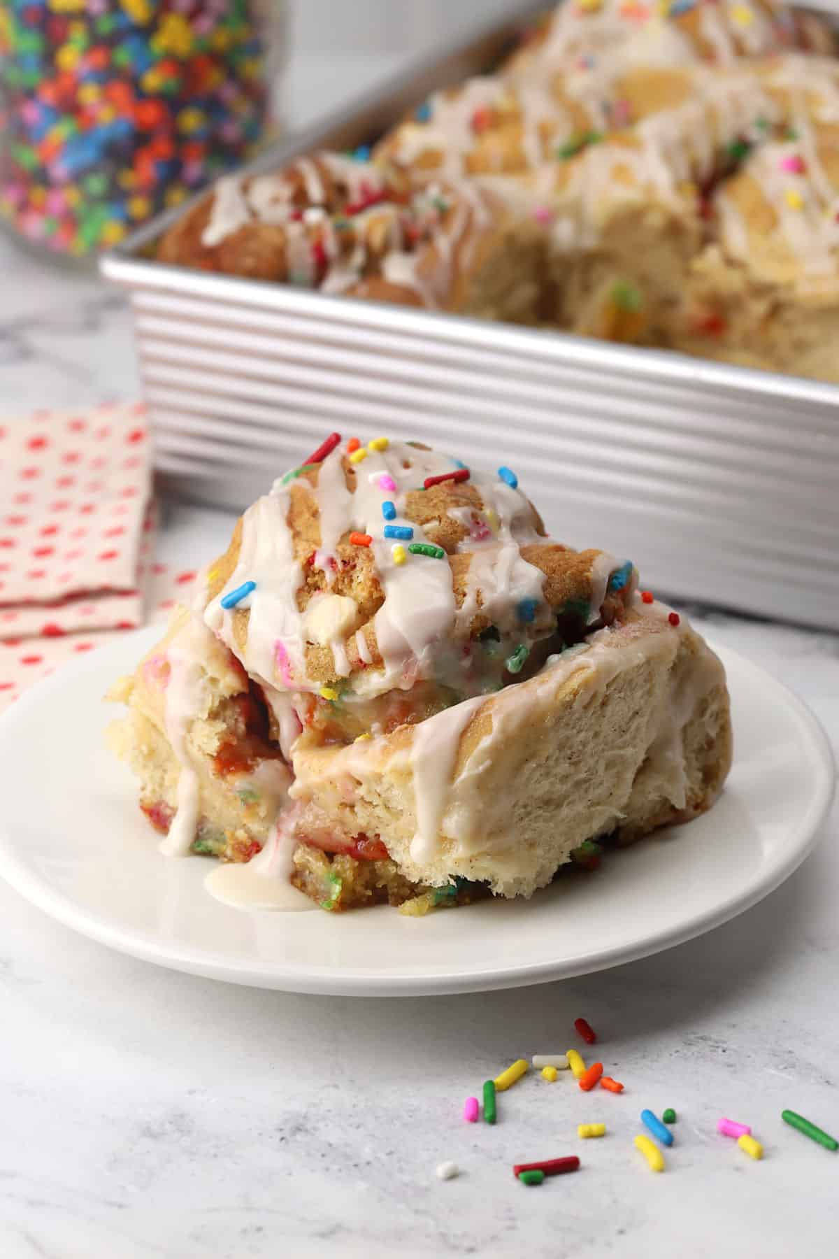 A birthday cookie cinnamon roll on a plate.