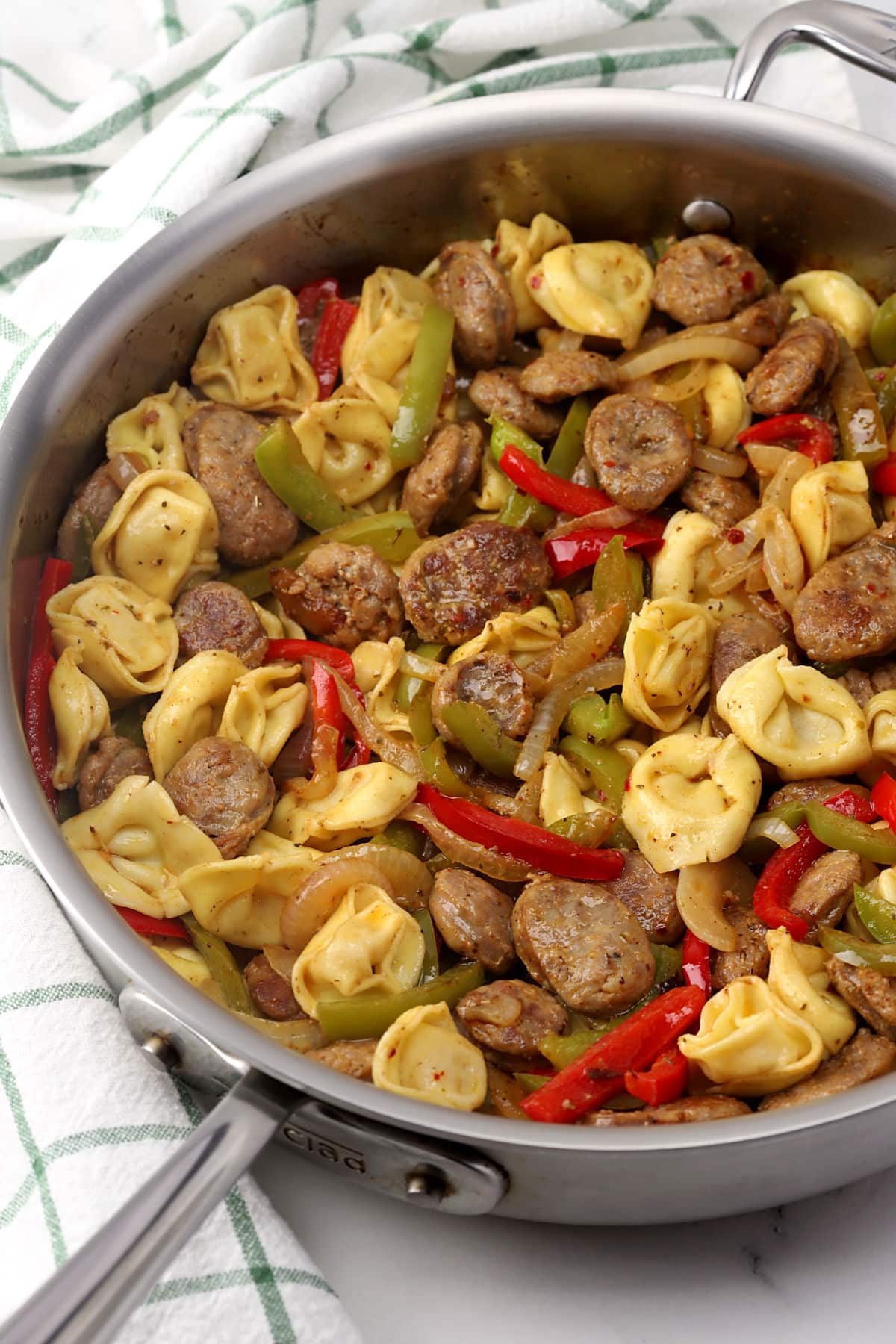 A pan of sausage, tortellini, and vegetables.