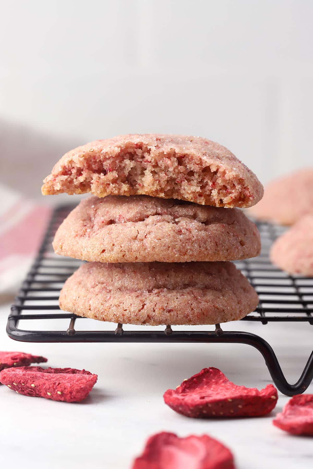 Strawberry sugar cookies stacked on a cooling rack.