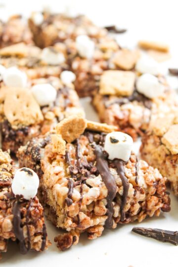 Squares of rice krispies treats with chocolate, graham cracker, and marshmallow.