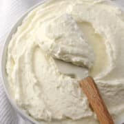 A wooden spatula scooping frosting from a bowl.