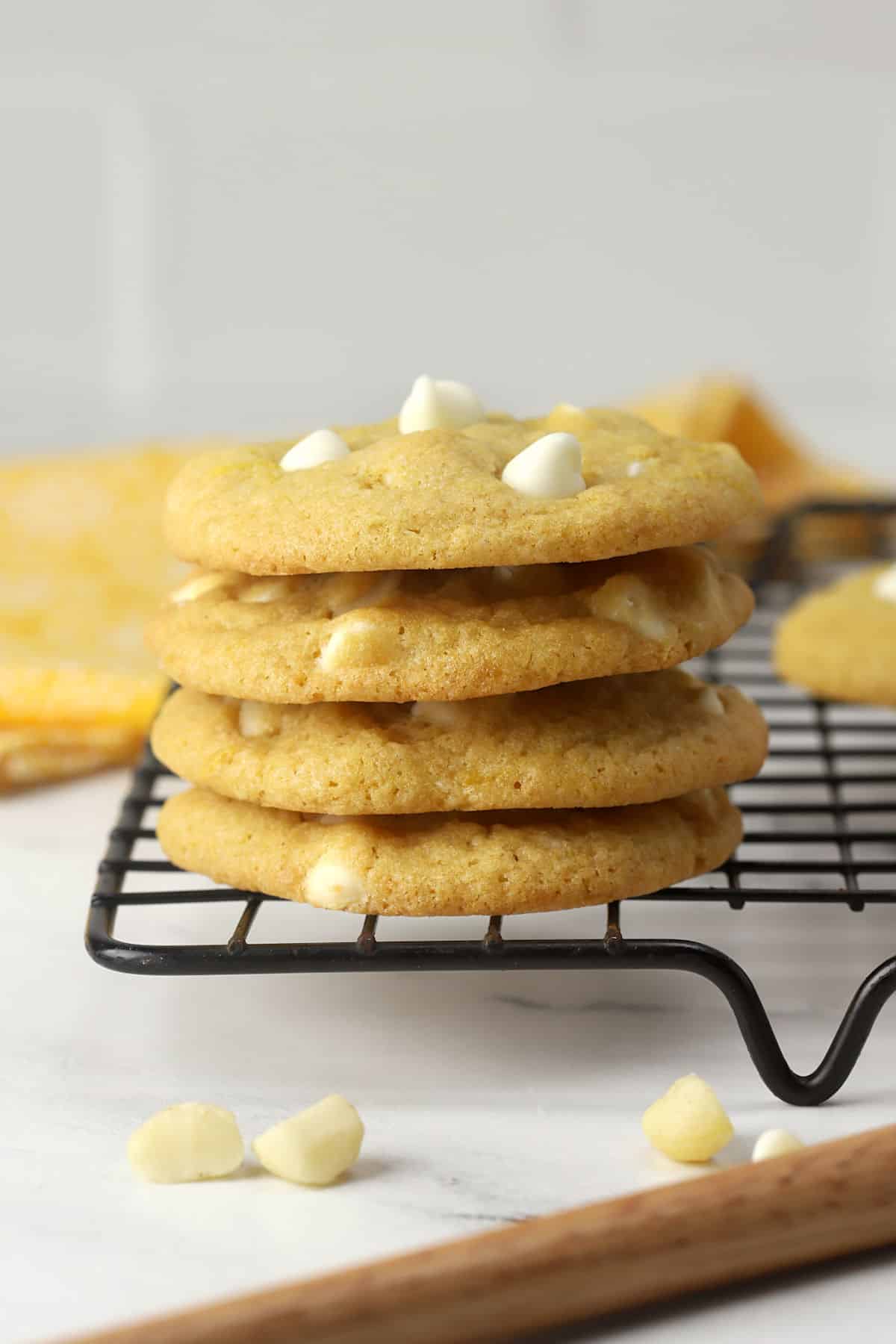 Lemon white chocolate macadamia nut cookies stacked on a cooling rack.