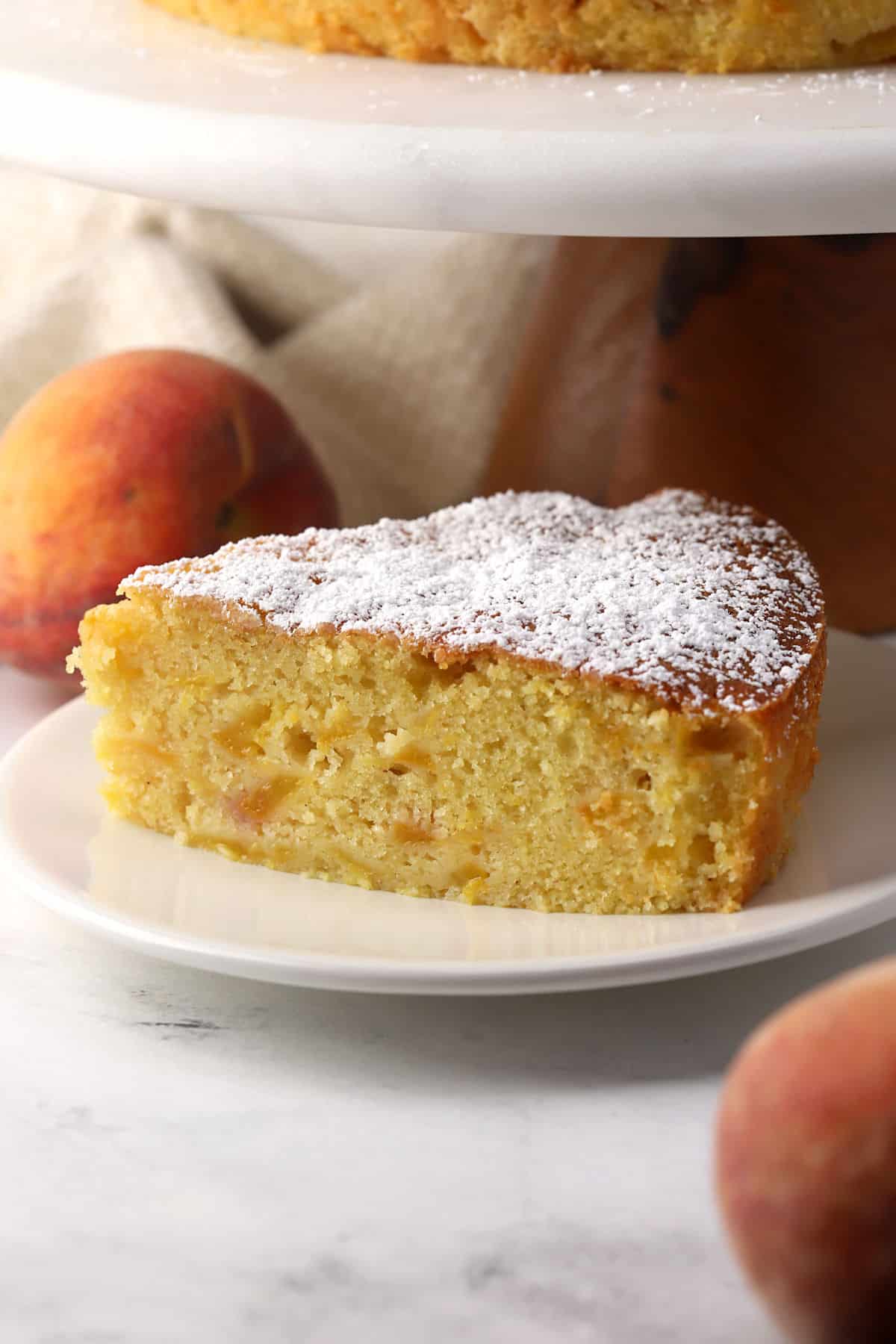 A slice of peach cake dusted with confectioner's sugar.