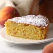 A slice of peach cake dusted with confectioner's sugar.