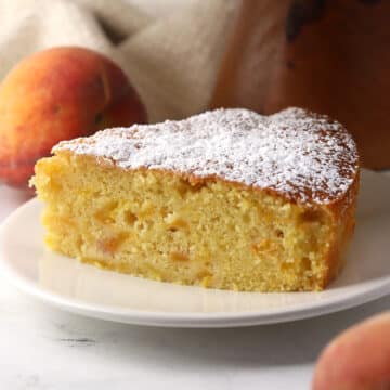 A slice of peach cake dusted with confectioner's sugar.