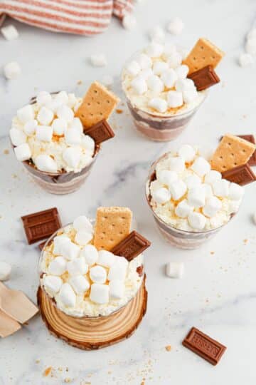Individual cups of pudding with marshmallow topping and graham cracker and chocolate garnish.